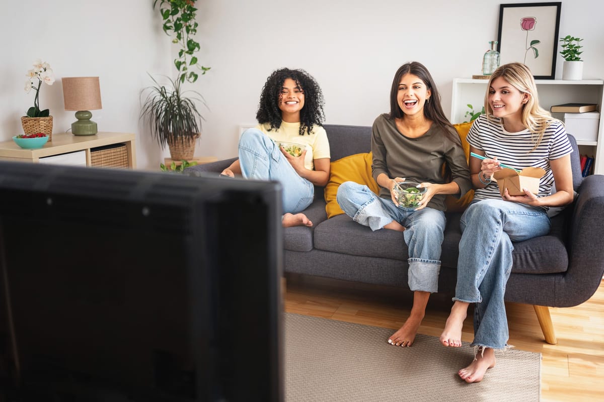 Drei junge Frauen lachen gemeinsam auf dem Sofa